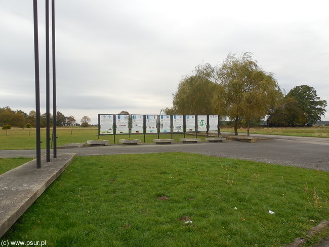 Rząd tablic informacyjnych przy parkingu koło pomnika