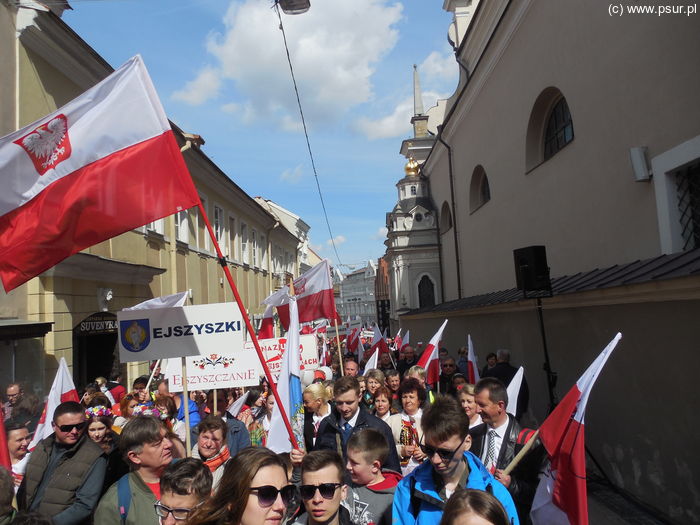 Wąska uliczka Wilna szczelnie wypełniona ludźmi z flagami Polski, transparentami itp.